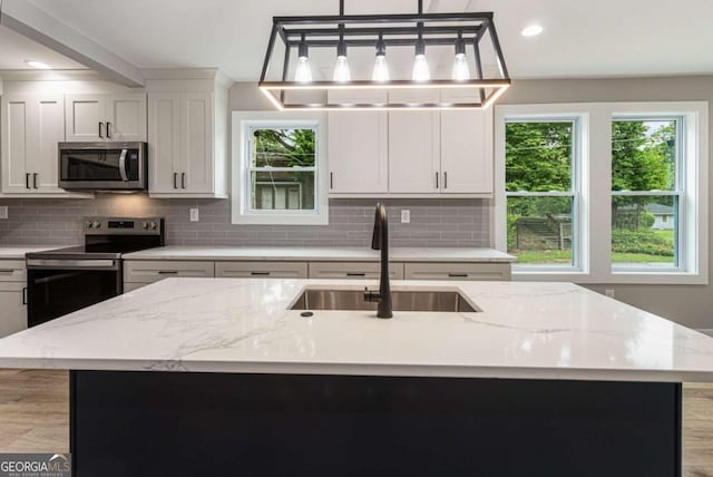 1283 Beecher St SW, Atlanta, GA 30310 - kitchen featuring stainless steel appliances, backsplash, light stone counters, a kitchen island with sink, and recessed lighting