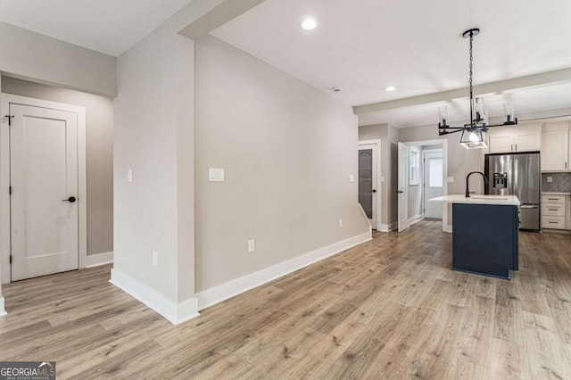 1283 Beecher St SW, Atlanta, GA 30310 - kitchen featuring stainless steel refrigerator with ice dispenser, light countertops, an island with sink, a chandelier, and light wood-style flooring