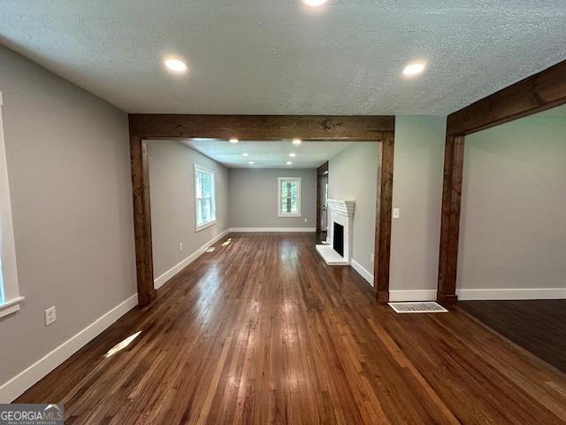 6538 N Sweetwater Rd, Lithia Springs, GA 30122 - unfurnished living room featuring dark wood finished floors, a fireplace with raised hearth, and a textured ceiling