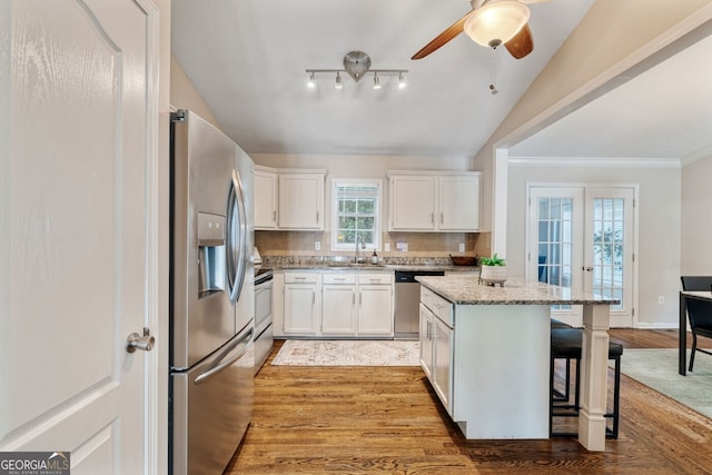 1087 Berkley Dr SE, Smyrna, GA 30082 - kitchen with stainless steel appliances, light stone countertops, a breakfast bar, white cabinetry, and light wood-type flooring