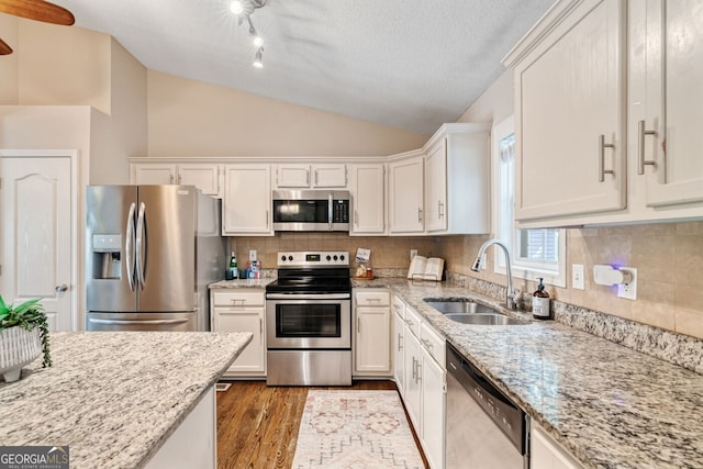 1087 Berkley Dr SE, Smyrna, GA 30082 - kitchen with stainless steel appliances, a sink, vaulted ceiling, wood finished floors, and white cabinets