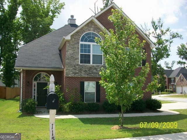 11599 Flemmings Cove Dr, Hampton, GA 30228 - view of front of house with a front yard, stone siding, a chimney, and brick siding