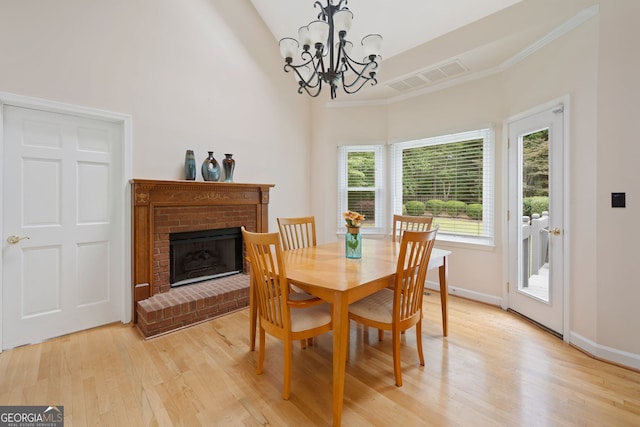 5711 Brynwood Cir NW, Acworth, GA 30101 - dining room with light wood-type flooring, a fireplace, a chandelier, baseboards, and a towering ceiling