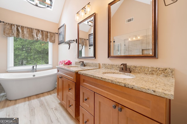 5711 Brynwood Cir NW, Acworth, GA 30101 - bathroom featuring lofted ceiling, double vanity, a freestanding bath, and wood finished floors