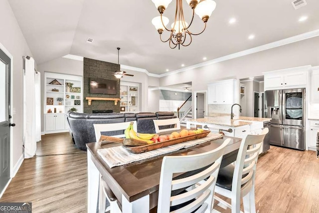 2980 Beards Rd, Buford, GA 30518 - dining space with ceiling fan, a stone fireplace, light wood-type flooring, a chandelier, and ornamental molding