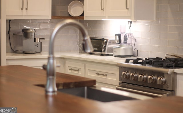603 W 1st St, Rome, GA 30161 - kitchen view of stainless steel range with gas stovetop, white cabinetry, light countertops, and backsplash
