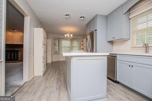 65 Pine Haven Ct, Carrollton, GA 30116 - kitchen with appliances with stainless steel finishes, a chandelier, wallpapered walls, light wood finished floors, and gray cabinetry