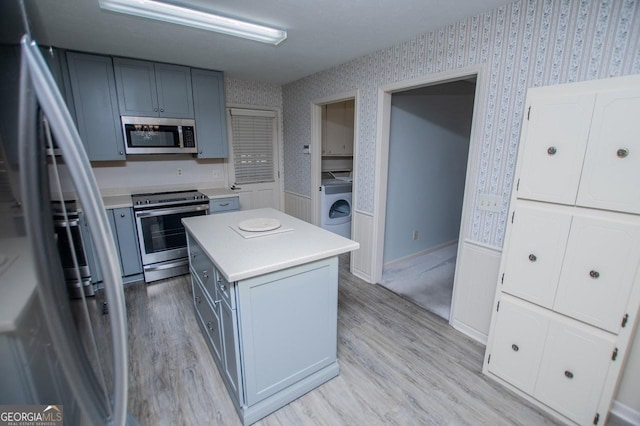 65 Pine Haven Ct, Carrollton, GA 30116 - kitchen with stainless steel appliances, wallpapered walls, washer / dryer, light countertops, and a kitchen island