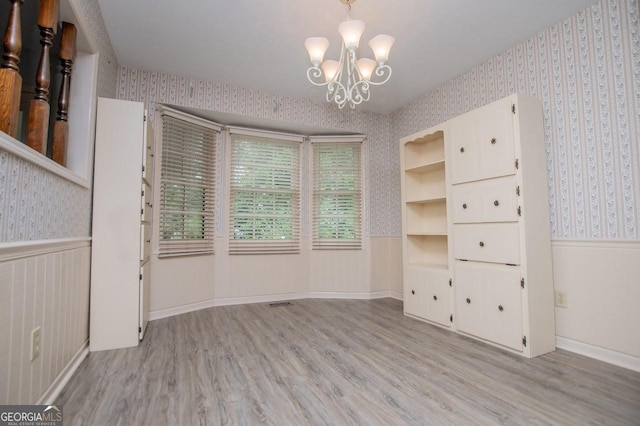 65 Pine Haven Ct, Carrollton, GA 30116 - empty room featuring wallpapered walls, light wood-type flooring, a chandelier, and a wainscoted wall
