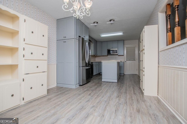 65 Pine Haven Ct, Carrollton, GA 30116 - kitchen featuring wallpapered walls, stainless steel appliances, gray cabinetry, a wainscoted wall, and light wood-style flooring