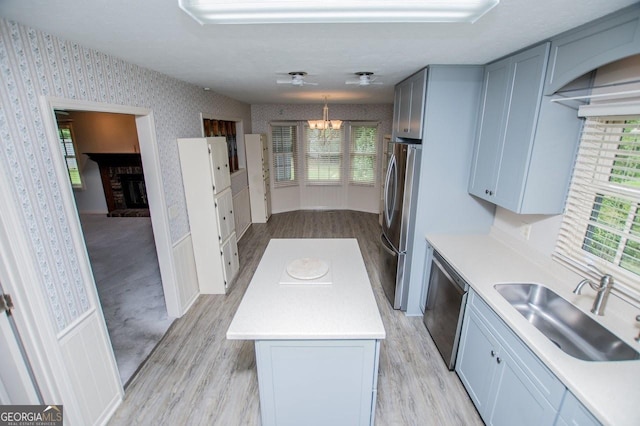 65 Pine Haven Ct, Carrollton, GA 30116 - kitchen with appliances with stainless steel finishes, a sink, wallpapered walls, a chandelier, and light wood-style flooring
