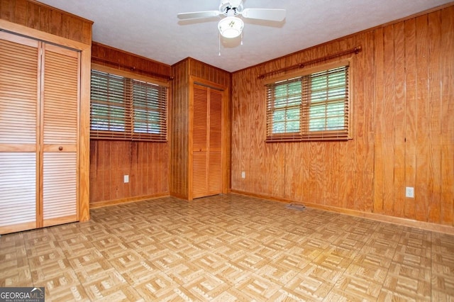 65 Pine Haven Ct, Carrollton, GA 30116 - unfurnished bedroom with multiple closets, baseboards, wooden walls, and ceiling fan