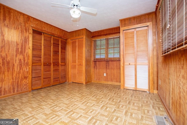 65 Pine Haven Ct, Carrollton, GA 30116 - unfurnished bedroom featuring wooden walls, multiple closets, baseboards, a ceiling fan, and crown molding
