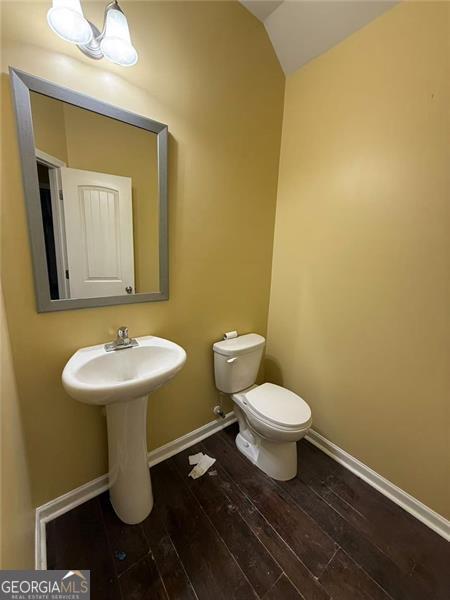 102 Daisy Cir, Mcdonough, GA 30252 - half bathroom with wood-type flooring, toilet, vaulted ceiling, and baseboards