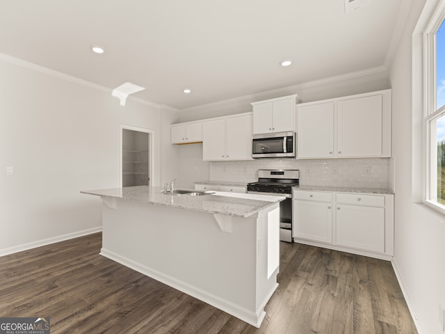 525 King Vlg, Braselton, GA 30517 - kitchen featuring appliances with stainless steel finishes, ornamental molding, white cabinets, tasteful backsplash, and a kitchen island with sink