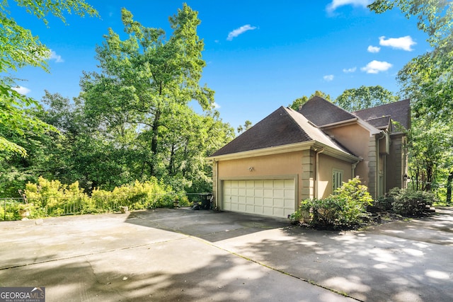 5105 Jett Forest Trl NW, Sandy Springs, GA 30327 - view of side of home featuring a garage, concrete driveway, stucco siding, and roof with shingles