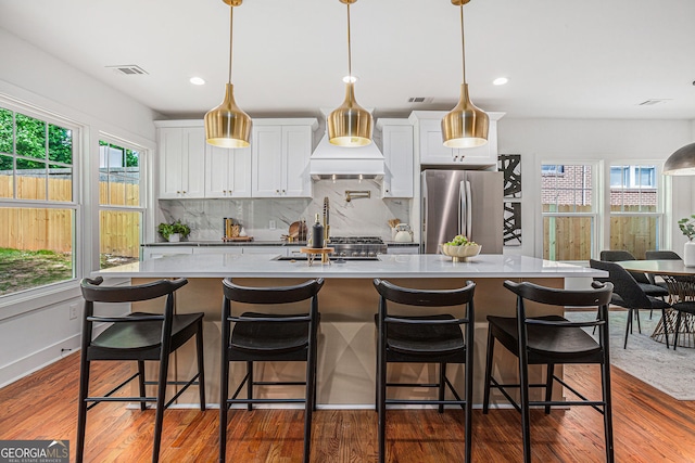 1721 S Gordon St SW, Atlanta, GA 30310 - kitchen with freestanding refrigerator, white cabinets, decorative backsplash, dark wood-type flooring, and an island with sink