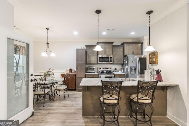 128 Arbor Crk, Warner Robins, GA 31093 - kitchen with stainless steel appliances, dark brown cabinets, a peninsula, a breakfast bar area, and light wood-style floors