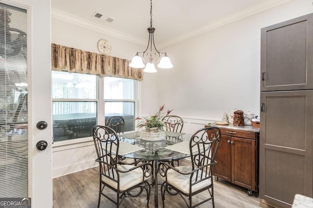 128 Arbor Crk, Warner Robins, GA 31093 - dining room with crown molding, light wood-style flooring, a chandelier, wainscoting, and a decorative wall