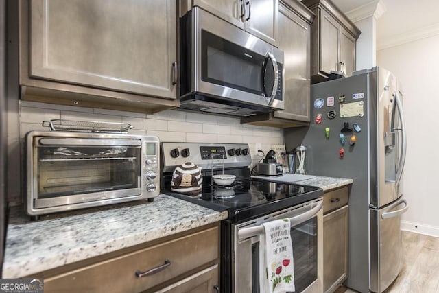 128 Arbor Crk, Warner Robins, GA 31093 - kitchen featuring stainless steel appliances, crown molding, backsplash, light stone counters, and light wood-type flooring