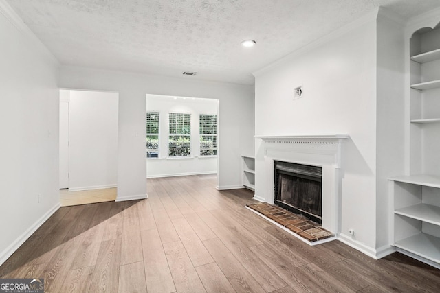 1931 Brian Way, Decatur, GA 30033 - unfurnished living room featuring a fireplace with raised hearth, wood finished floors, built in shelves, a textured ceiling, and ornamental molding