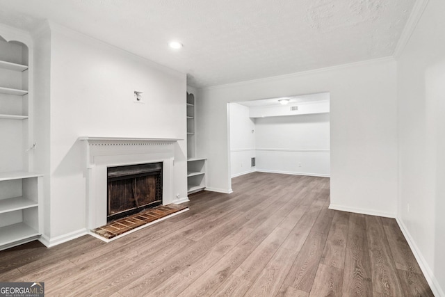 1931 Brian Way, Decatur, GA 30033 - unfurnished living room with built in shelves, ornamental molding, wood finished floors, a fireplace with raised hearth, and a textured ceiling