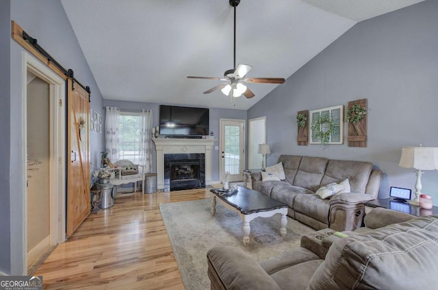 62 Lazy Water Dr SW, Cartersville, GA 30120 - living room with light wood finished floors, ceiling fan, a barn door, a premium fireplace, and high vaulted ceiling