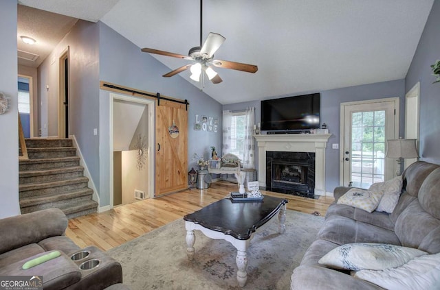 62 Lazy Water Dr SW, Cartersville, GA 30120 - living area with a barn door, a ceiling fan, lofted ceiling, wood finished floors, and a premium fireplace