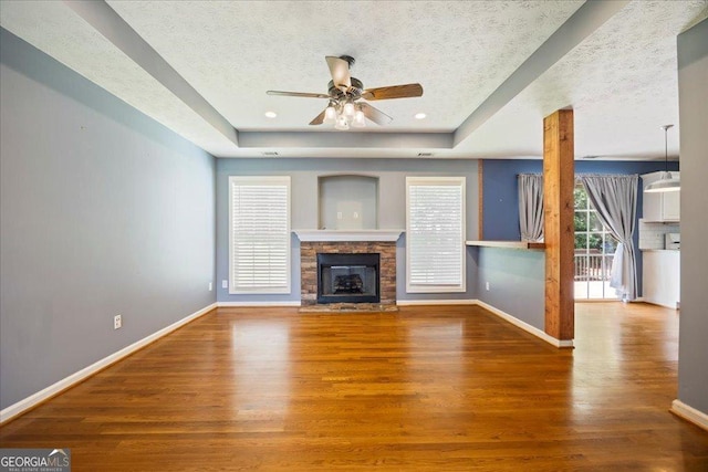 7825 Running Fox Trl, Gainesville, GA 30506 - unfurnished living room with wood finished floors, ceiling fan, a raised ceiling, a fireplace, and a textured ceiling