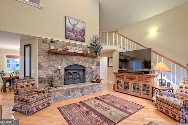 4505 Mccullum Trl, Hiawassee, GA 30546 - living room featuring a high ceiling, hardwood / wood-style floors, a stone fireplace, stairway, and baseboards