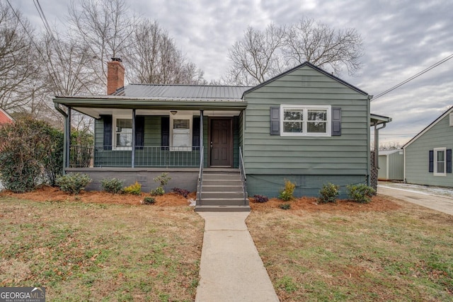 4131 Carroll St SW, Covington, GA 30014 - bungalow featuring a chimney, covered porch, a metal roof, and a front yard