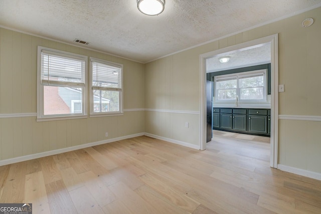 4131 Carroll St SW, Covington, GA 30014 - empty room with light wood-style floors, ornamental molding, a decorative wall, and a textured ceiling