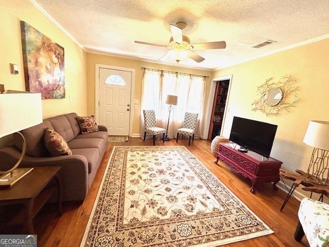 315 Clairborne Ave, Statesboro, GA 30458 - living room featuring crown molding, a textured ceiling, a ceiling fan, wood finished floors, and baseboards