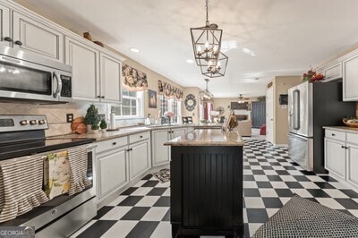 154 Hunters Trl, Dallas, GA 30157 - kitchen with appliances with stainless steel finishes, dark flooring, a chandelier, a center island, and light countertops