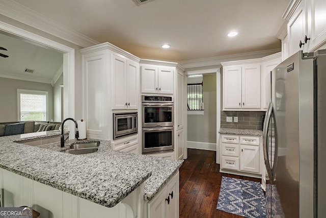 1015 Turtle Pond Dr, Watkinsville, GA 30677 - kitchen featuring appliances with stainless steel finishes, a sink, ornamental molding, dark wood-type flooring, and white cabinets