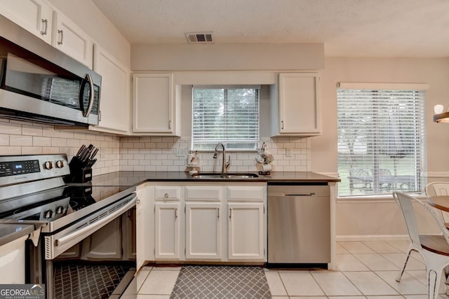 3694 Jay Bird Aly, Peachtree Corners, GA 30092 - kitchen with appliances with stainless steel finishes, a sink, light tile patterned flooring, dark countertops, and white cabinets