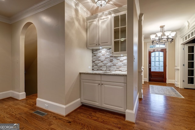 1984 Mendenhall Cir, Atlanta, GA 30341 - bar featuring crown molding, dark wood-style floors, a chandelier, arched walkways, and backsplash