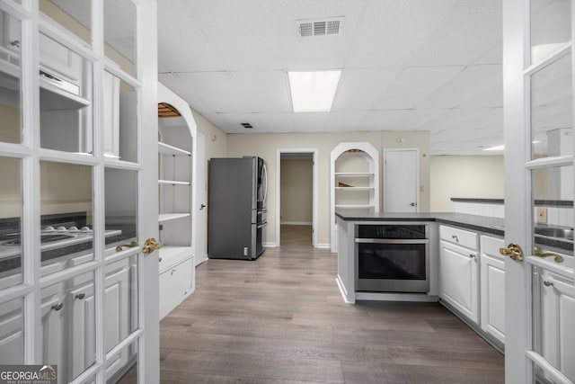 5065 Nesbit Ferry Ln, Atlanta, GA 30350 - kitchen featuring appliances with stainless steel finishes, dark wood finished floors, white cabinetry, dark countertops, and a drop ceiling