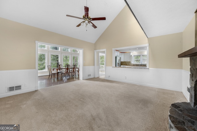 5065 Nesbit Ferry Ln, Atlanta, GA 30350 - living room featuring wainscoting, a fireplace with raised hearth, ceiling fan, light carpet, and high vaulted ceiling