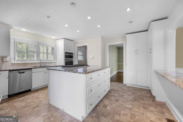5065 Nesbit Ferry Ln, Atlanta, GA 30350 - kitchen with stainless steel appliances, a kitchen island, recessed lighting, dark stone counters, and white cabinetry