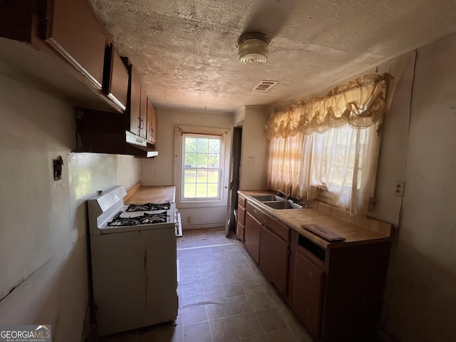 1263 Highland Ave, Macon, GA 31211 - kitchen featuring gas range gas stove, a sink, a textured ceiling, under cabinet range hood, and tile patterned floors