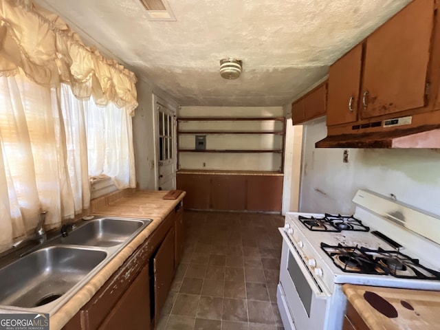 1263 Highland Ave, Macon, GA 31211 - kitchen with white gas stove, under cabinet range hood, a sink, brown cabinetry, and light countertops