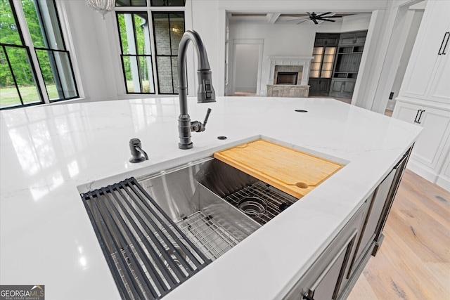 4927 Slaton Dr, Acworth, GA 30101 - kitchen with a fireplace, white cabinetry, light wood-style flooring, ceiling fan, and open floor plan