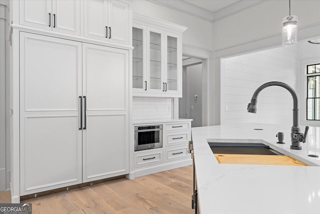 4927 Slaton Dr, Acworth, GA 30101 - kitchen with white cabinets, light wood-type flooring, glass insert cabinets, decorative light fixtures, and light stone counters