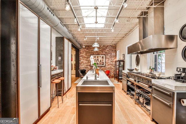 1933 Mclendon Ave NE Unit A, Atlanta, GA 30307 - kitchen with exhaust hood, a sink, track lighting, light wood-style flooring, and brick wall