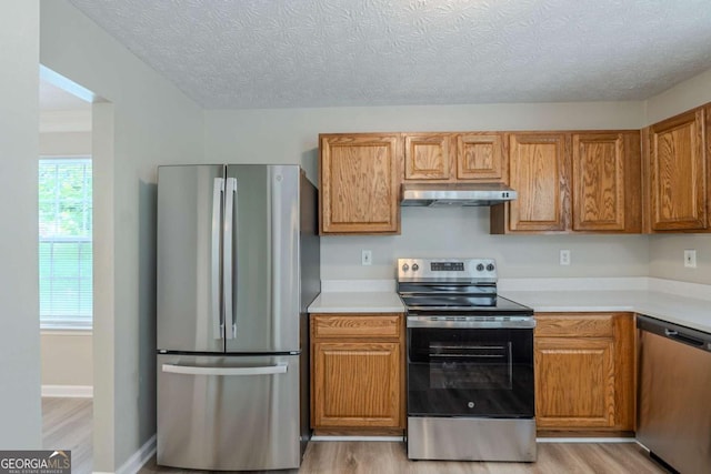 589 Arbor Ridge Dr, Stone Mountain, GA 30087 - kitchen with appliances with stainless steel finishes, under cabinet range hood, light wood finished floors, light countertops, and a textured ceiling