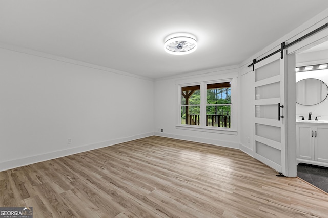 8129 S Giles Rd, Douglasville, GA 30135 - empty room featuring a barn door, light wood finished floors, and ornamental molding