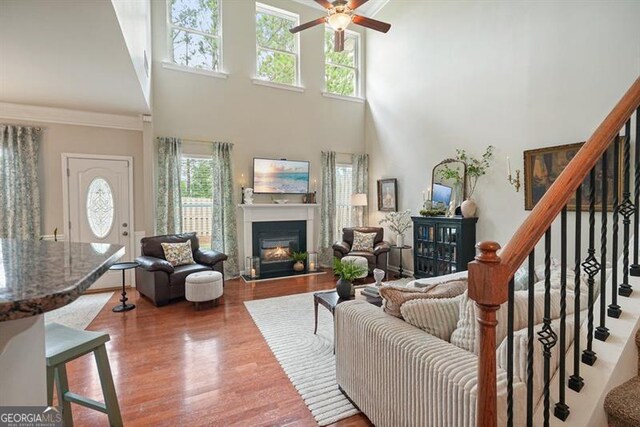 411 Mountain View Ln, Woodstock, GA 30188 - living area featuring a towering ceiling, a glass covered fireplace, plenty of natural light, stairs, and a ceiling fan