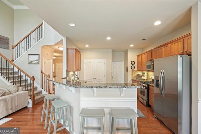 411 Mountain View Ln, Woodstock, GA 30188 - kitchen with appliances with stainless steel finishes, light stone counters, wood finished floors, a breakfast bar area, and recessed lighting