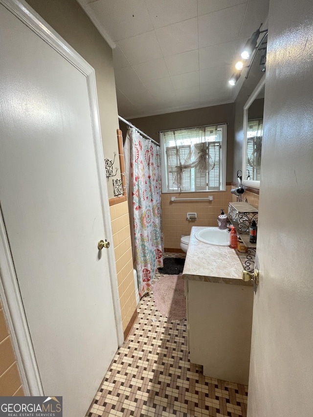 2742 Forest Ridge Dr, Macon, GA 31204 - bathroom featuring tile patterned floors, vanity, tile walls, curtained shower, and wainscoting